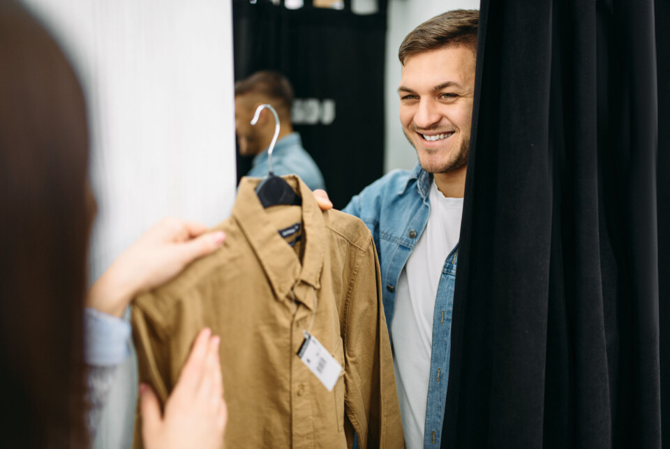 4: I prøverommet mann i prøverom mottar skjorte fra kvinne