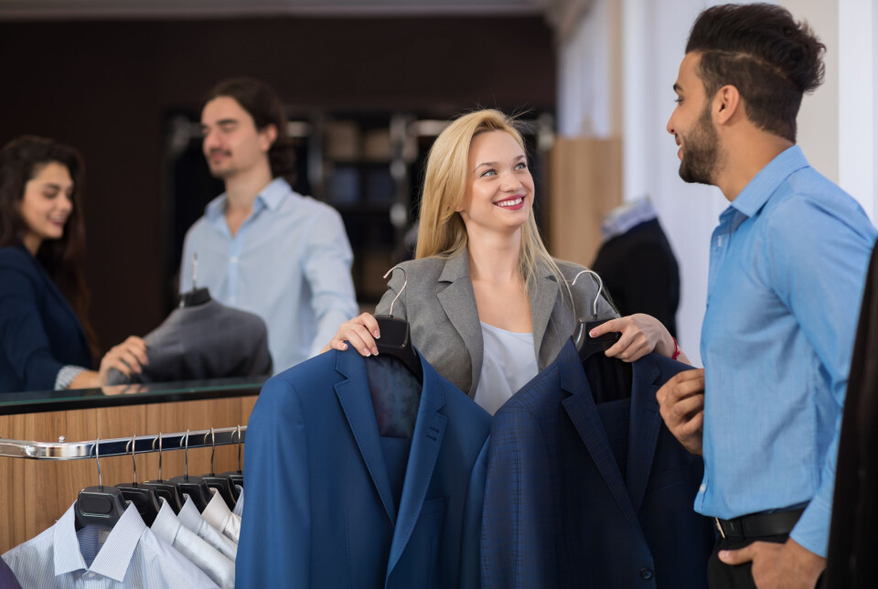 7: Kundemøte er kommunikasjon kvinne viser en mann to dressjakker i en klesbutikk